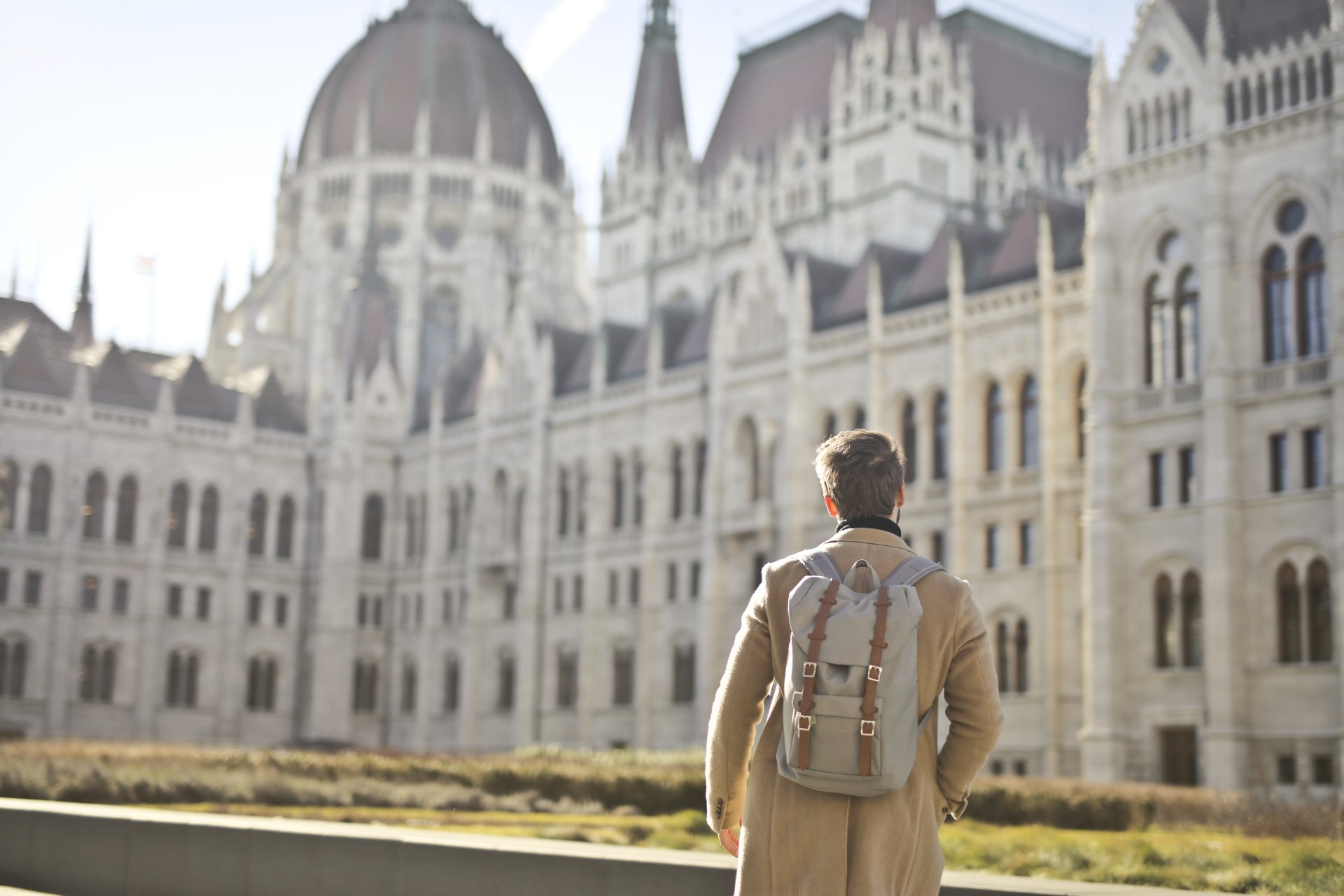 背着双肩包的年轻男子站在布达佩斯的匈牙利国会大厦前